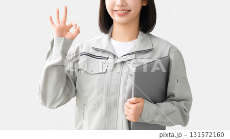 パソコンを持ってOKポーズをする作業服を着た若い女性 パソコンを持ってOKポーズをする作業服を着た若い女性 131572160