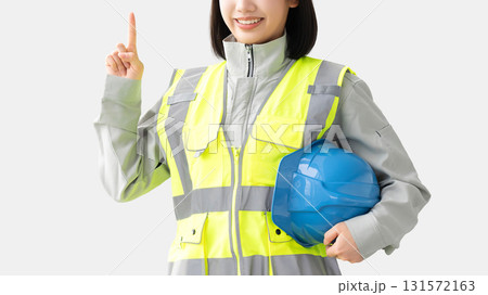 反射ベストと作業服を着てヘルメット持つ笑顔の女性 反射ベストと作業服を着てヘルメット持つ笑顔の女性 131572163
