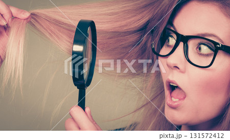 Woman holding magnifying glass looking at hair 131572412
