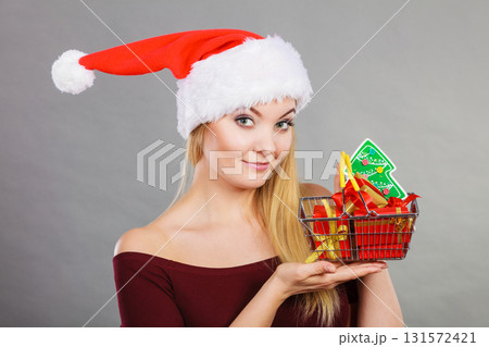 Santa woman holding shopping cart with christmas gifts Santa woman holding shopping cart with christmas gifts 131572421