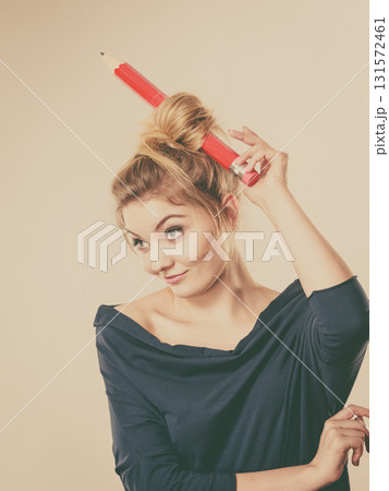 Happy blonde woman having big pencil in hair 131572461