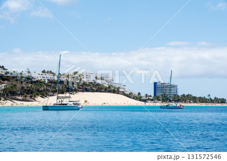 海から見える白い砂浜と白いリゾートホテルと地層の見える茶色のはげ山　フエルテベンテュラ島にて 131572546