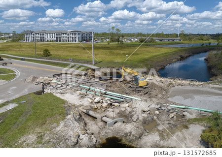 Construction equipment at roadworks site. Reconstruction of damaged road bridge destroyed by river after flood water washed away asphalt. Rebuilding of ruined transportation infrastructure 131572685