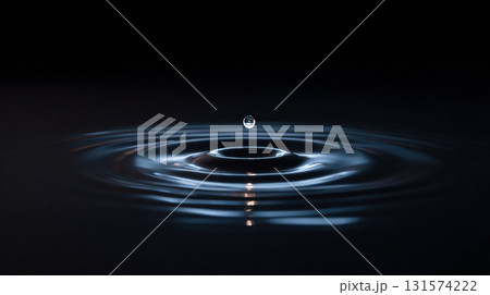 Single drop of liquid falls into calm dark pool creating serene ripple effect. beautiful concentric circle and reflection evoke feeling of tranquility and peace 131574222