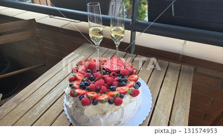 Elegant celebration with berry pavlova and champagne on rustic balcony setting. Happy birthday Elegant celebration with berry pavlova and champagne on rustic balcony setting. Happy birthday 131574953
