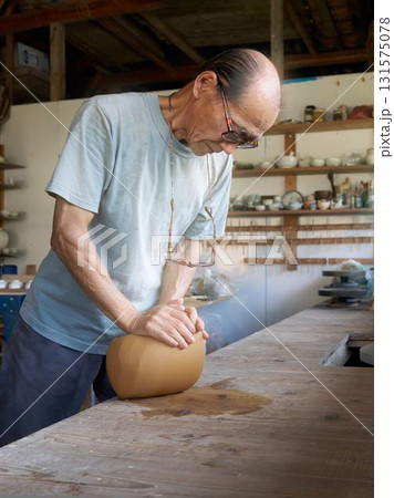 陶芸工房で土を練るベテラン職人 131575078