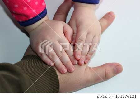 Little children's hands pressed the big hand of an adult to a white surface 131576121