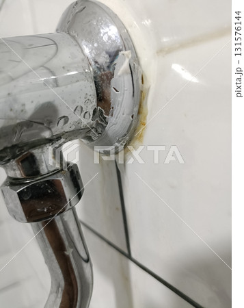 Shiny chrome pipe bathroom tile white grout caulk peeling water stains rust mark plumbing fixture wet surface 131576144