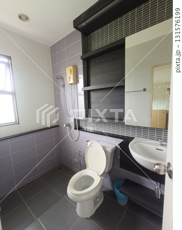 Modern bathroom interior with open toilet seat, wall shower, sink and shelving creating clean functional space with soft light and muted tile tones Modern bathroom interior with open toilet seat, wall shower, sink and shelving creating clean functional space with soft light and muted tile tones 131576199