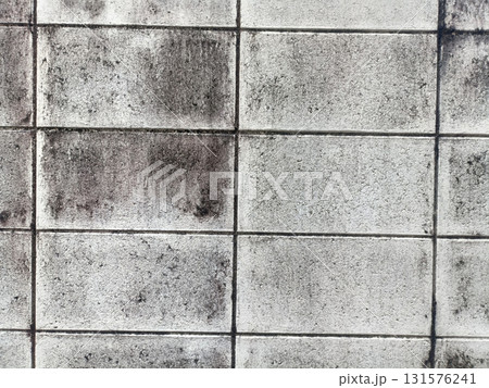 Weathered concrete block wall with mold stains and grid pattern conveying urban decay and texture Weathered concrete block wall with mold stains and grid pattern conveying urban decay and texture 131576241
