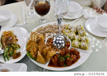 Festive platter of assorted Chinese dim sum and appetizers on round serving tray with dipping bowl and iced drinks, inviting family meal and celebration scene Festive platter of assorted Chinese dim sum and appetizers on round serving tray with dipping bowl and iced drinks, inviting family meal and celebration scene 131576258