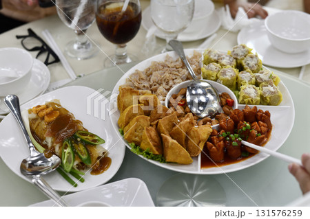 Steamed dumpling, fried wonton, sausage in sauce, rice roll with peanut sauce and sliced chili, assorted Chinese dim sum platter served on round table with glasses and bowls Steamed dumpling, fried wonton, sausage in sauce, rice roll with peanut sauce and sliced chili, assorted Chinese dim sum platter served on round table with glasses and bowls 131576259