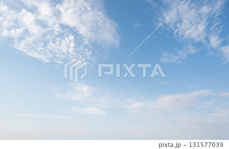 Clear sky with scattered white clouds. The clouds vary in size and shape, creating a serene atmosphere. Background light blue. Clear sky with scattered white clouds. The clouds vary in size and shape, creating a serene atmosphere. Background light blue. 131577039
