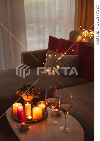 Cozy evening scene with candles, wine glasses and warm lighting. Cozy evening scene with candles, wine glasses and warm lighting. 131577327