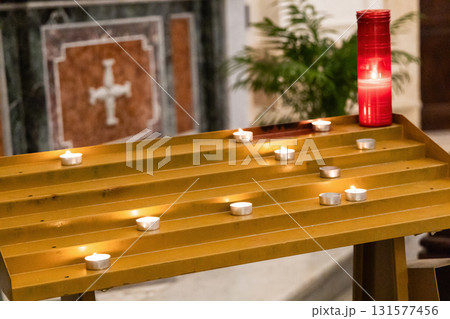 Glowing candles in sacred catholic church interior 131577456