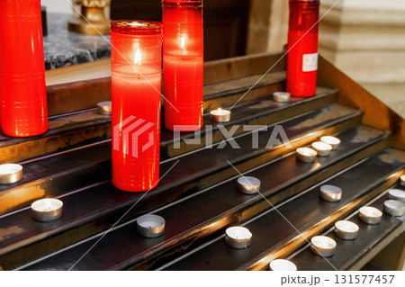 Burning candles illuminating peaceful catholic church interior Burning candles illuminating peaceful catholic church interior 131577457