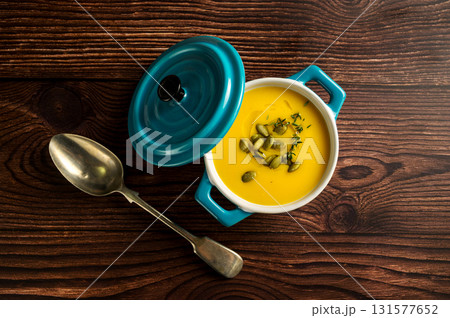 Pumpkin soup in ceramic blue bowl, wooden background, top view 131577652