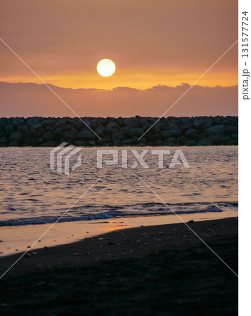 A serene beach scene at sunset with gentle waves lapping at the shore. Tenerife beach with volcanic black sand 131577724