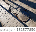 Sewer Manhole on the Street Near Sidewalk Showing Wear and Surrounding Pavement 131577850