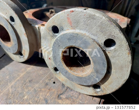 Cast Iron Industrial Pump Housing Flanges Displayed on a Wooden Workbench in a Workshop Setting 131577852