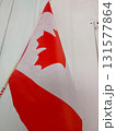 Canadian Flag Waving Against a White Wooden Background During Daylight Hours 131577864