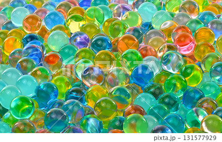 A bunch of colorful marbles are scattered on a surface 131577929