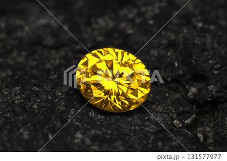 A yellow diamond is sitting on a black rock 131577977