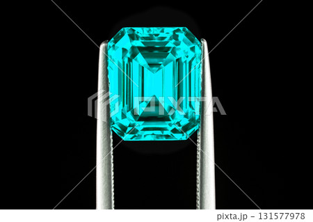 A blue gemstone is being held up by a metal tool A blue gemstone is being held up by a metal tool 131577978