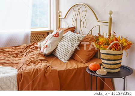 Cozy autumn bedroom interior with warm bedding, pillows, Halloween pumpkins and seasonal decoration 131578356