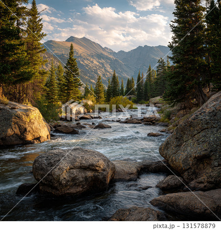Majestic mountain landscapes at sunset, featuring a rocky river flowing through a forest with pine trees and large boulders. 131578879