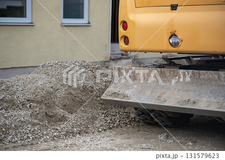 Heavy Excavator Bucket Attached To Yellow Construction Machinery: Dirt Ground And Greenery Background At Worksite 131579623