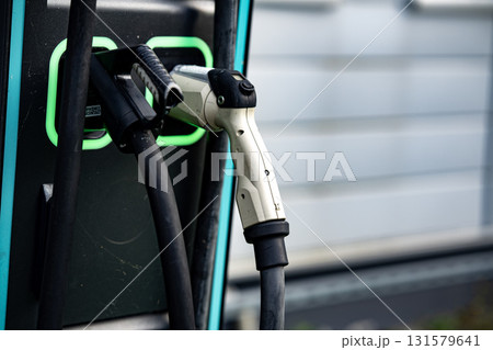 Electric Vehicle Charging Station With Dual Connectors: Close-Up Of Modern EV Power Supply Cables And Sockets With Green LED Outlines On Black Panel In Urban Setting 131579641