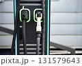 Electric Vehicle Charging Station With Dual Connectors: Close-Up Of Modern EV Power Supply Cables And Sockets With Green LED Outlines On Black Panel In Urban Setting 131579643