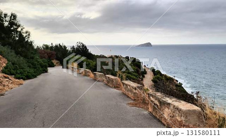 A scenic road that leads directly to the vast ocean on a cloudy day 131580111