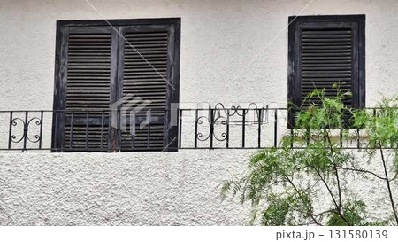 A charming white building with black shutters and a balcony tree 131580139