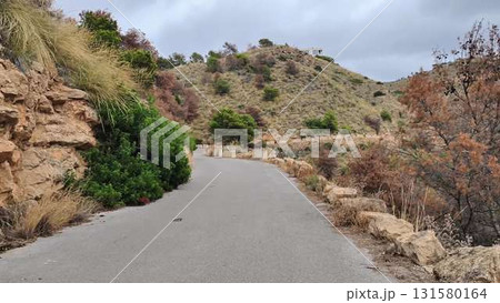 A scenic road climbs a hill, offering stunning mountain views 131580164
