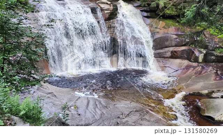 A stunningly beautiful waterfall gracefully flowing over rocky surfaces in a forested area 131580269
