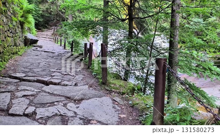 A scenic and picturesque stone pathway meanders gracefully alongside a serene riverbank A scenic and picturesque stone pathway meanders gracefully alongside a serene riverbank 131580273