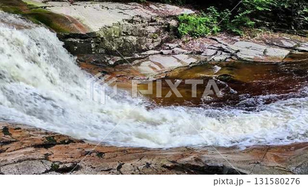 Soothing and Relaxing Waterfall Flowing Over Rocks Surrounded by Lush Green Forests 131580276