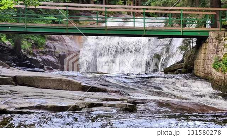 A serene waterscape featuring a beautiful bridge accompanied by a stunning cascading waterfall A serene waterscape featuring a beautiful bridge accompanied by a stunning cascading waterfall 131580278