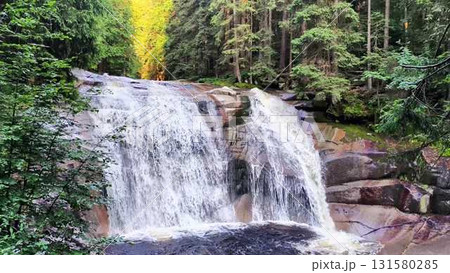 A stunningly beautiful natural waterfall elegantly surrounded by lush, vibrant greenery 131580285