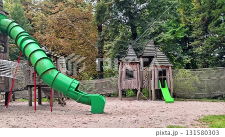 A colorful playground with a large green slide and wooden structures for kids to explore A colorful playground with a large green slide and wooden structures for kids to explore 131580303