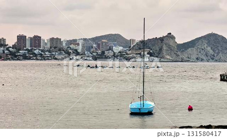A Tranquil Seaside Scene with a Beautiful Sailboat and Stunning Cityview in the Background A Tranquil Seaside Scene with a Beautiful Sailboat and Stunning Cityview in the Background 131580417