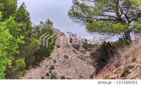 Experience breathtaking views of a hilltop building surrounded by lush greenery, inviting adventure Experience breathtaking views of a hilltop building surrounded by lush greenery, inviting adventure 131580501