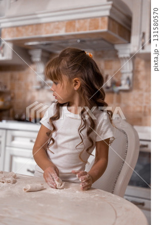 young girl is focused on making a cake. Flour dusts the table as she shapes dough gaining confidence in her baking skills. 131580570