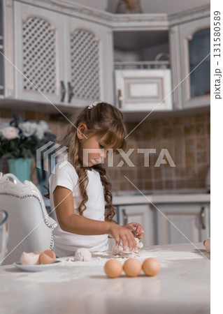 young girl carefully kneads dough while surrounded by eggs and flour. She is focused on creating a delicious cake showcasing her love for baking. young girl carefully kneads dough while surrounded by eggs and flour. She is focused on creating a delicious cake showcasing her love for baking. 131580589