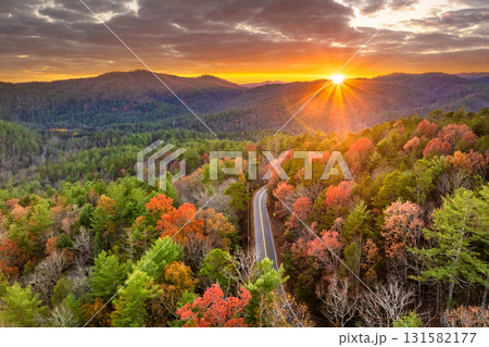 Car cruising on scenic road in Appalachian mountains at sunset. Trees glowing in vibrant fall foliage as the sun sets Car cruising on scenic road in Appalachian mountains at sunset. Trees glowing in vibrant fall foliage as the sun sets 131582177