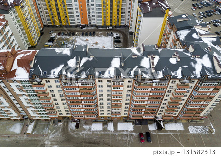 Aerial winter top view of tall apartment building, brick chimneys, tiled roof. Urban infrastructure, view from above. Aerial winter top view of tall apartment building, brick chimneys, tiled roof. Urban infrastructure, view from above. 131582313