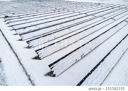 Aerial view of sustainable electrical power plant with solar photovoltaic panels covered with snow in winter for producing clean energy. Concept of low effectivity of renewable electricity in north Aerial view of sustainable electrical power plant with solar photovoltaic panels covered with snow in winter for producing clean energy. Concept of low effectivity of renewable electricity in north 131582335