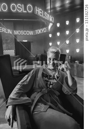 Smiling Woman in Robe Under Neon City Names 131582726